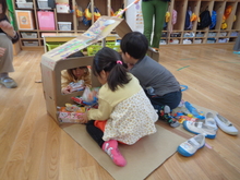 空き箱で作った車を段ボールで作った車庫に片づけています。