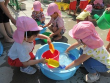 スコップで水をすくって、バケツに入れています